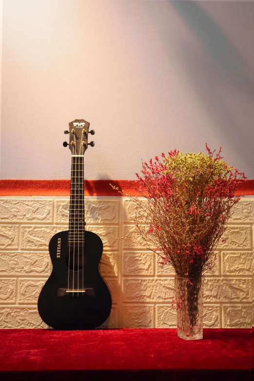 a guitar and vase of flowers on a ledge