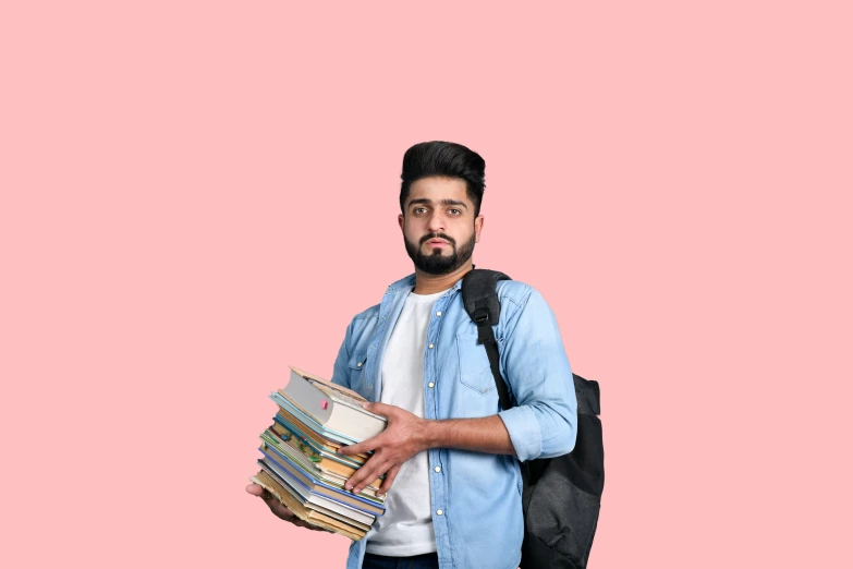 man holding a stack of books in front of a pink background