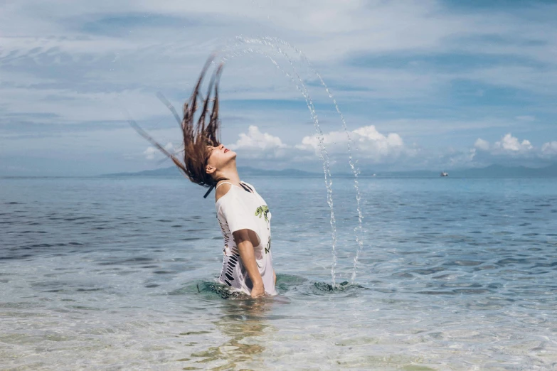 a woman standing in the water holding her hair