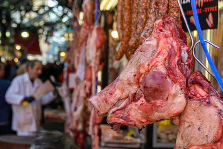 a couple of bunches of meat hanging in front of some people