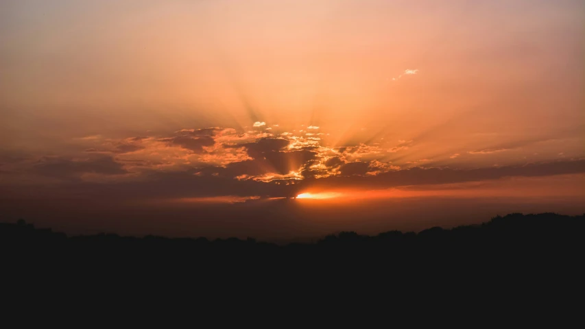 a sunset seen through clouds above a forest