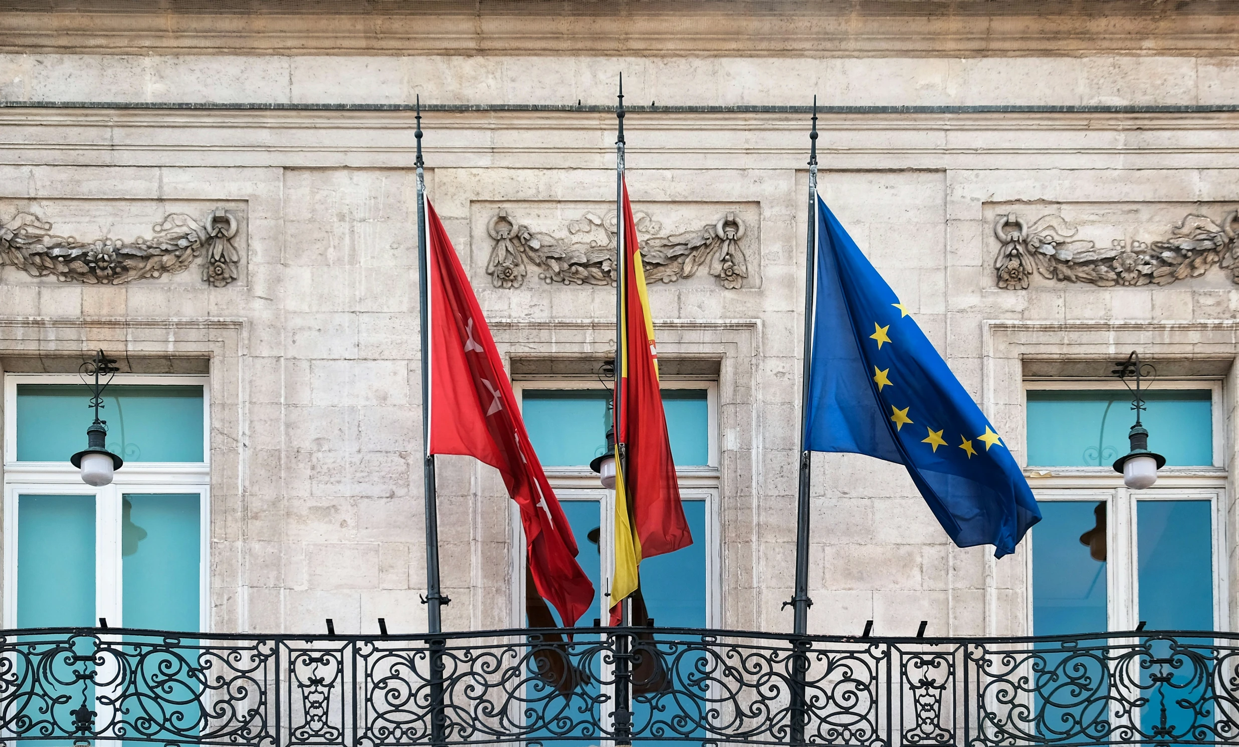 there are some flags next to an iron fence