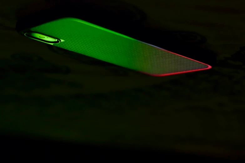 a close up of a green cell phone in the dark