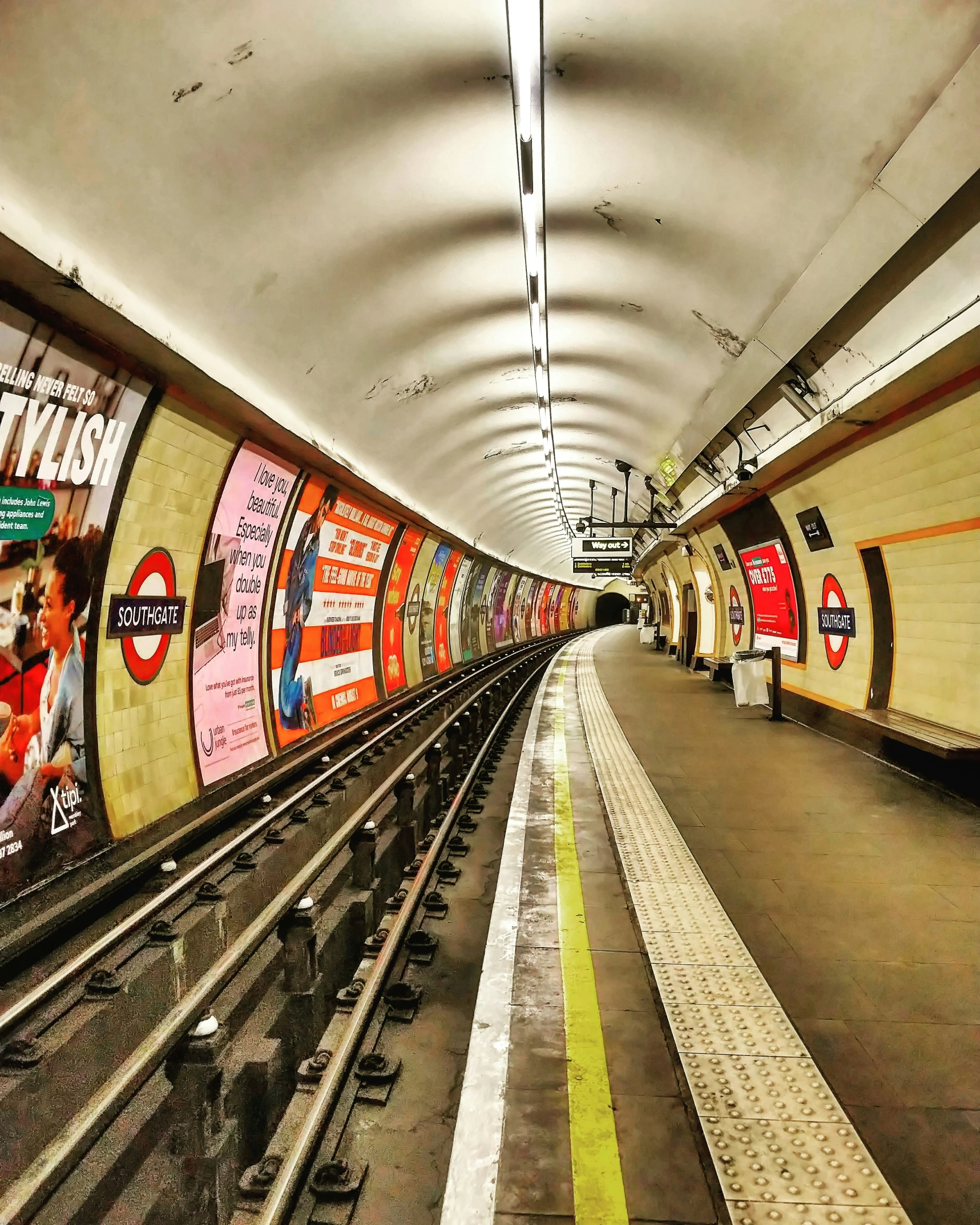 a subway platform with train tracks and empty benches