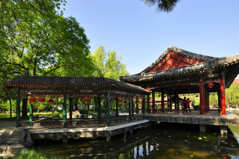 a pond is seen behind a pavilion in the middle of a park