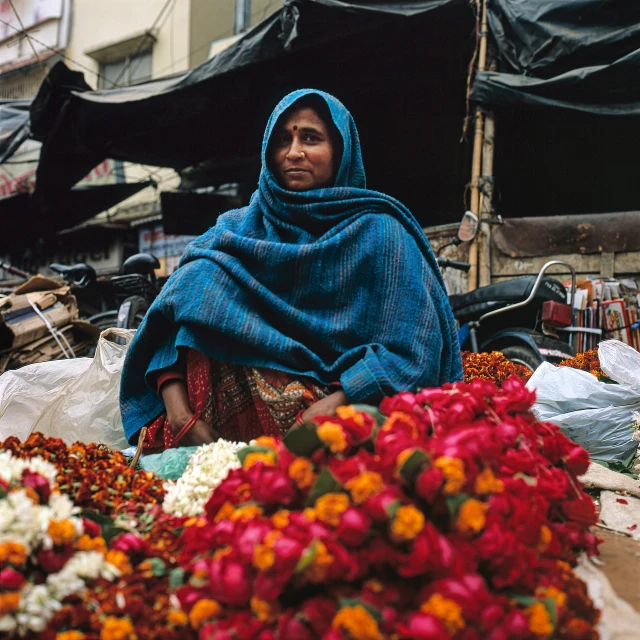 an indian woman is sitting next to colorful flowers