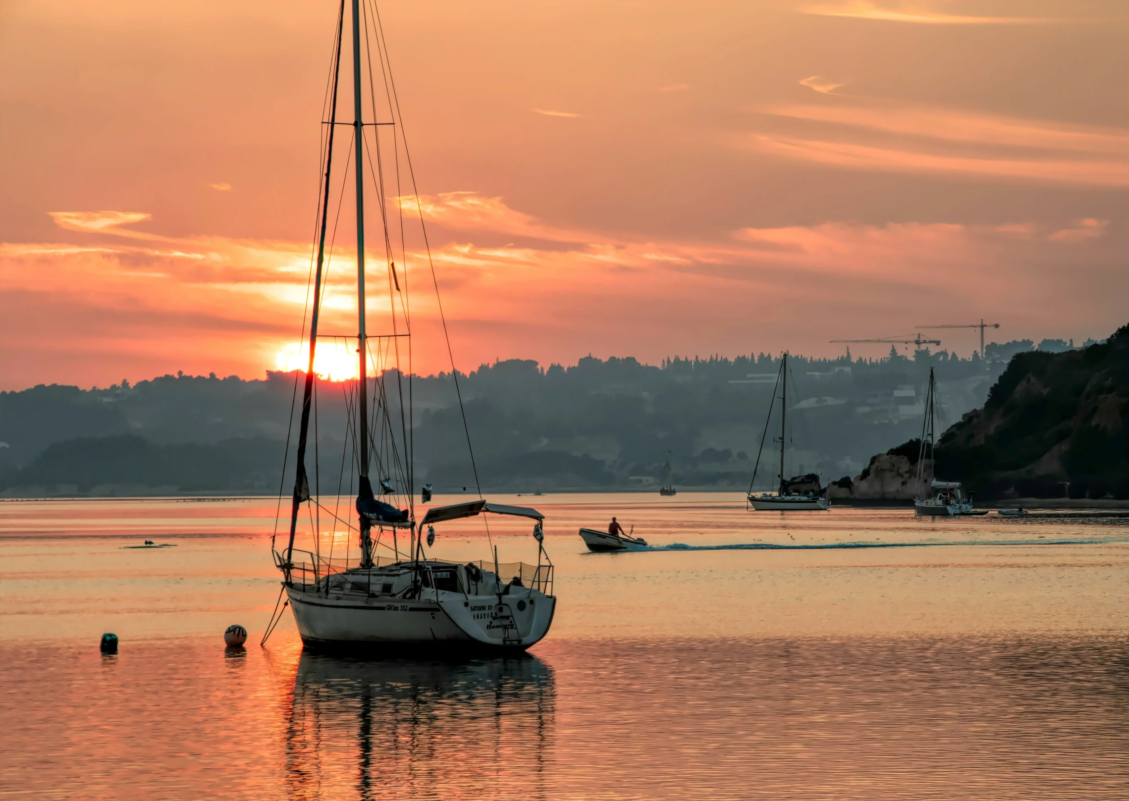 several boats in water with the sun setting behind them