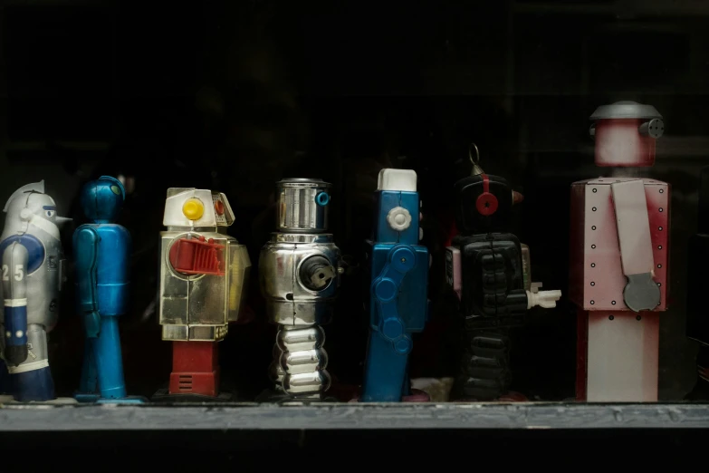 five tin toy robots are sitting in the window