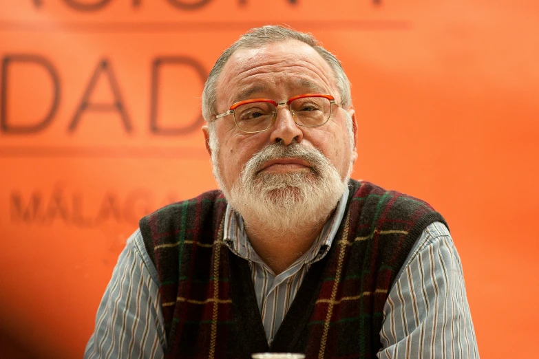 man with glasses sitting at the top of a table