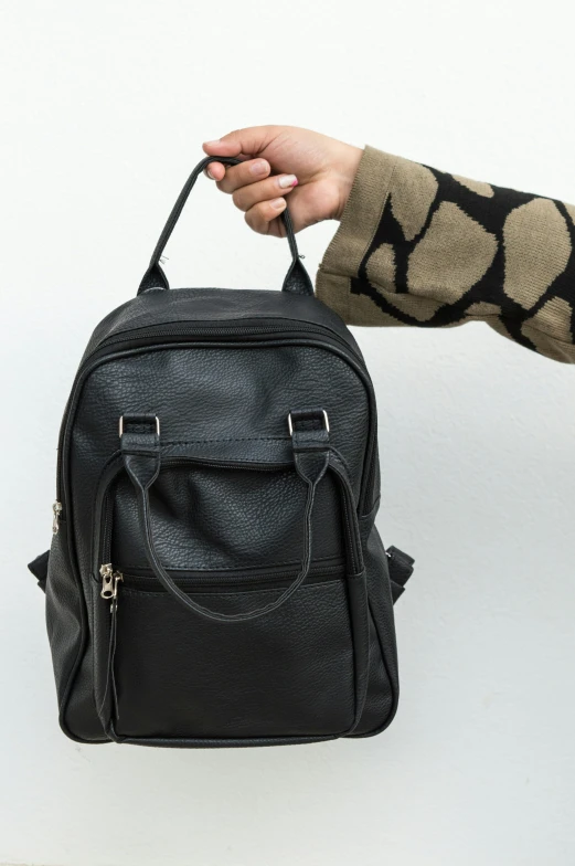 a hand is holding onto a black backpack