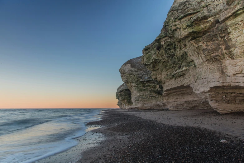 the view of a rocky beach next to a cliff