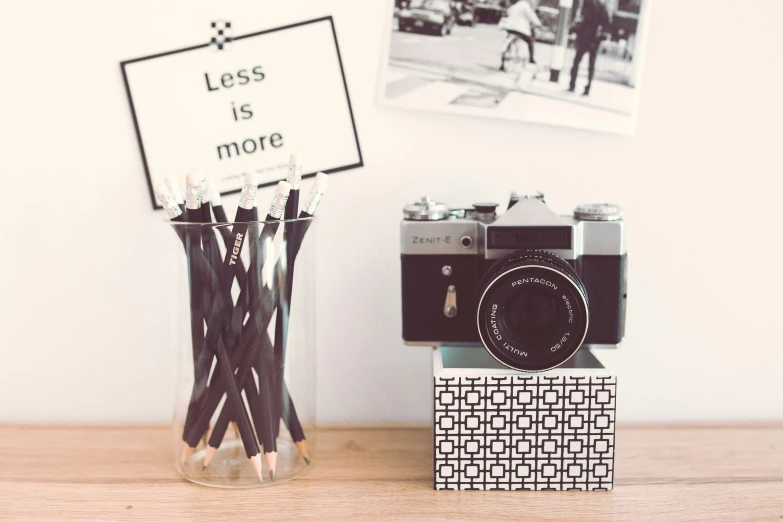 pencils and camera sitting on top of a wooden table