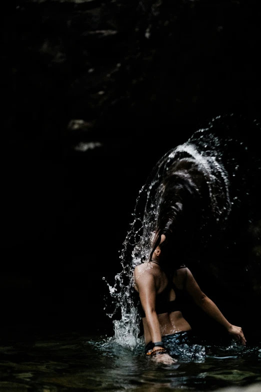 a girl playing in water spraying her hair up