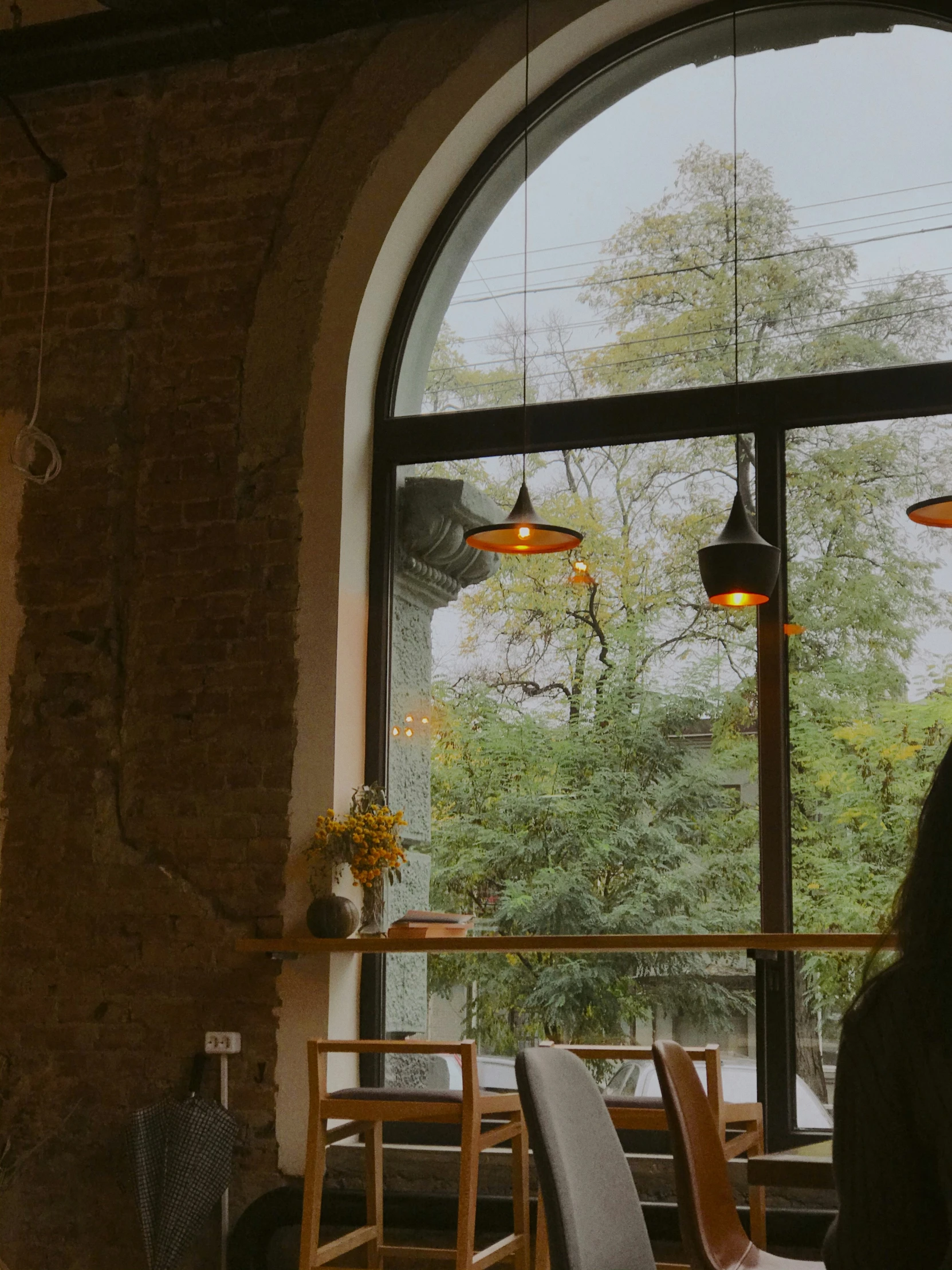 a woman looks out an arched window at a table and chairs