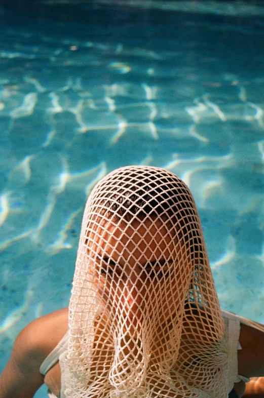 the view of a woman with a mesh veil on her head and a swimming pool