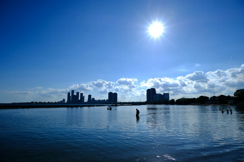 some boats on the water and buildings under a bright blue sky