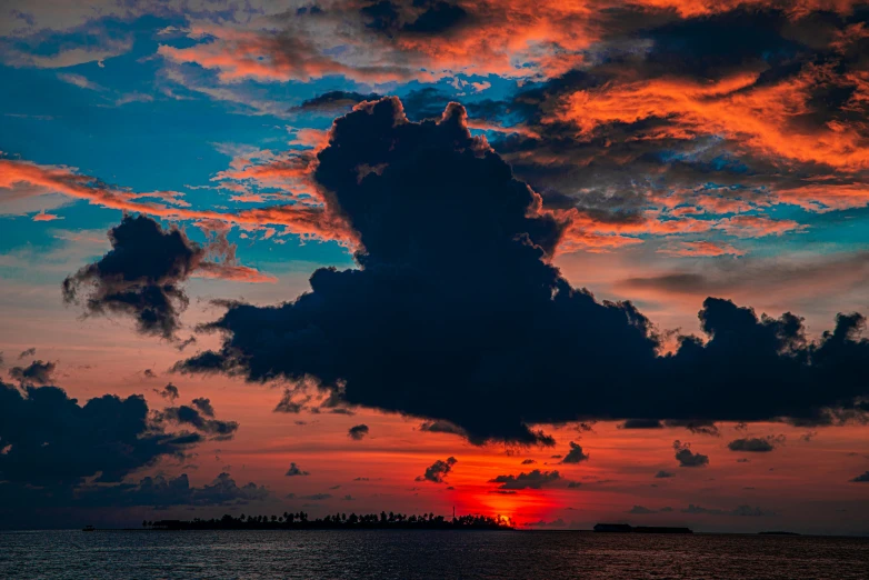 clouds are blowing over the ocean at sunset