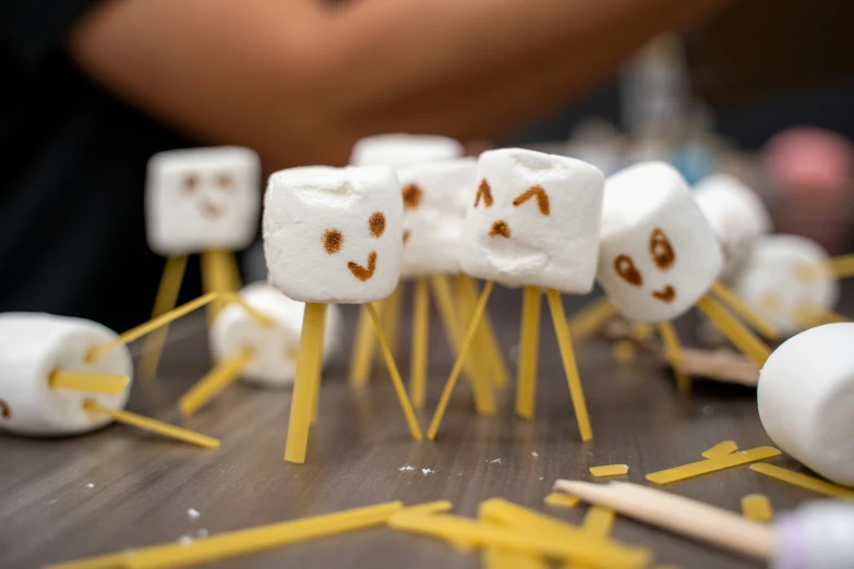 a couple of marshmallows that are on wooden sticks