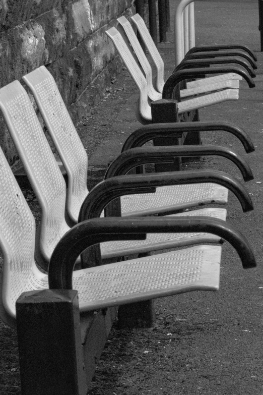 an assortment of park benches are lined up along a wall