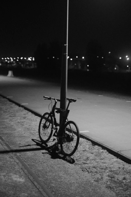 a bike parked next to a street lamp on the side of a road