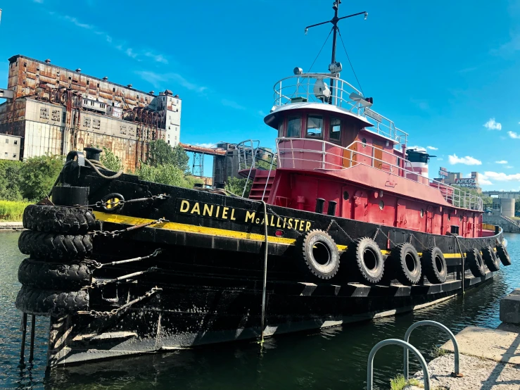 a black and red tugboat sits on the water