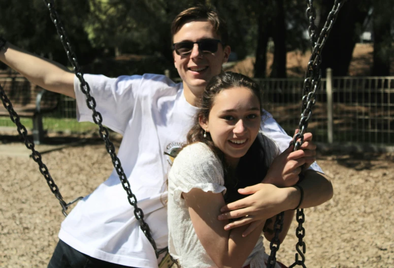 a man and a  are hugging on a swing