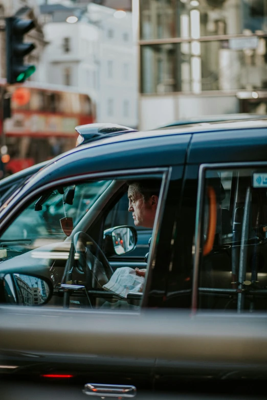 a taxi cab and driver are stopped at traffic light