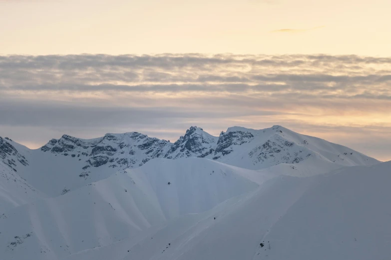 a group of skiers standing in the snow near mountain tops