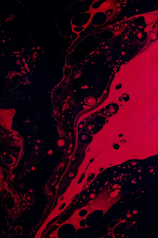 red and black liquid floating on top of a black surface