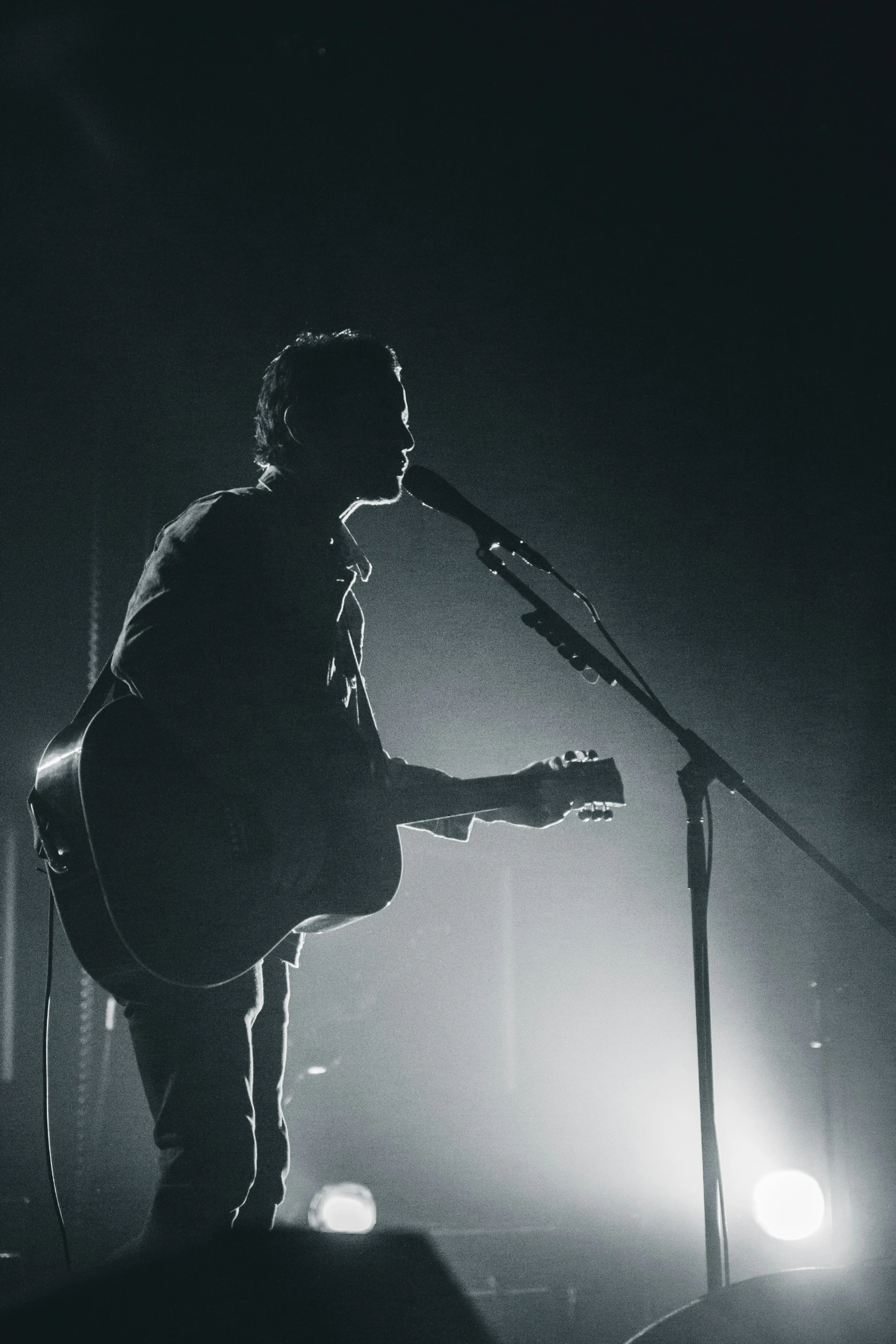 a man with a guitar stands on stage at the microphone