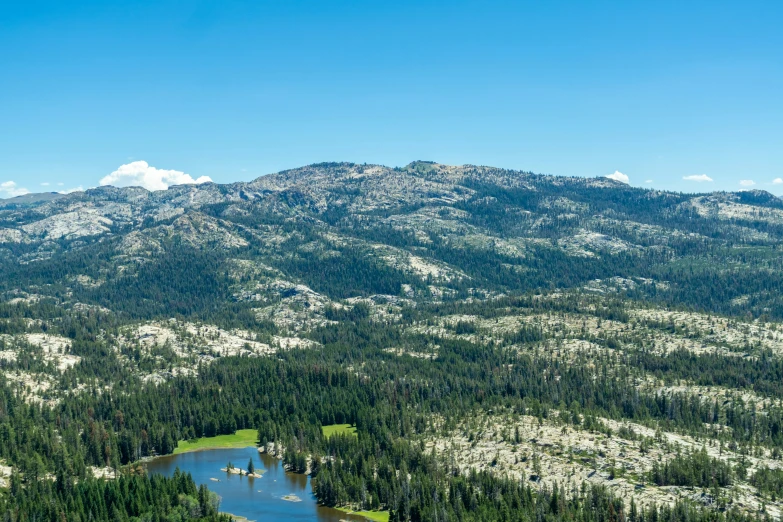 a large field and lake in the middle of a mountain