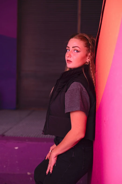 the girl is leaning against the pink and orange wall