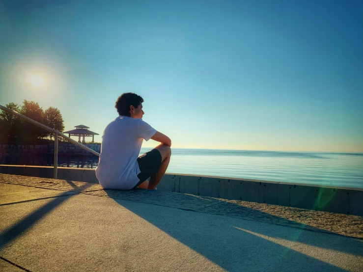 a man sitting on top of a road next to the ocean