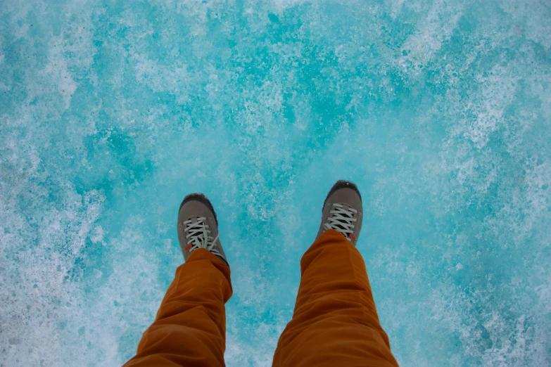 person's feet standing by a water surface