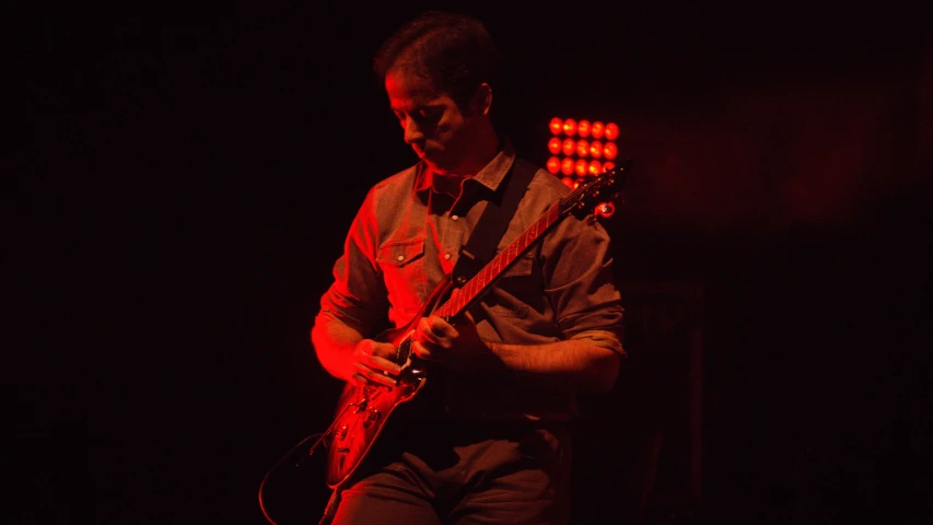 the man with his guitar is playing in the dark