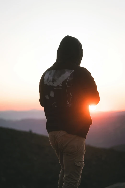 a person is standing in front of a sunset