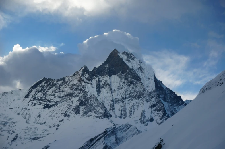 mountain range covered with snow and clouds under blue sky