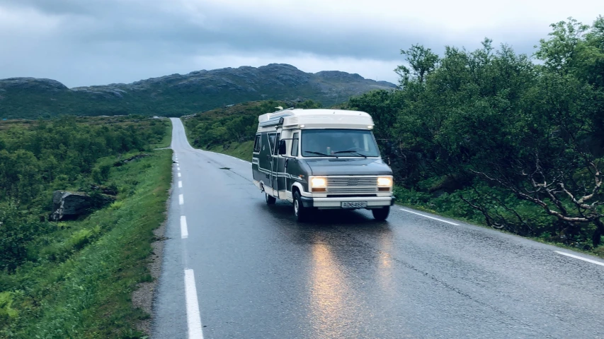 a van is driving down the road on a rainy day