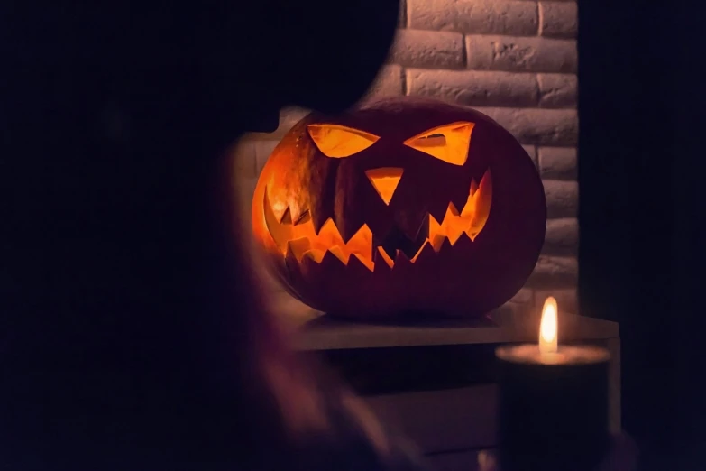 the glowing jack o lantern is displayed beside a candle