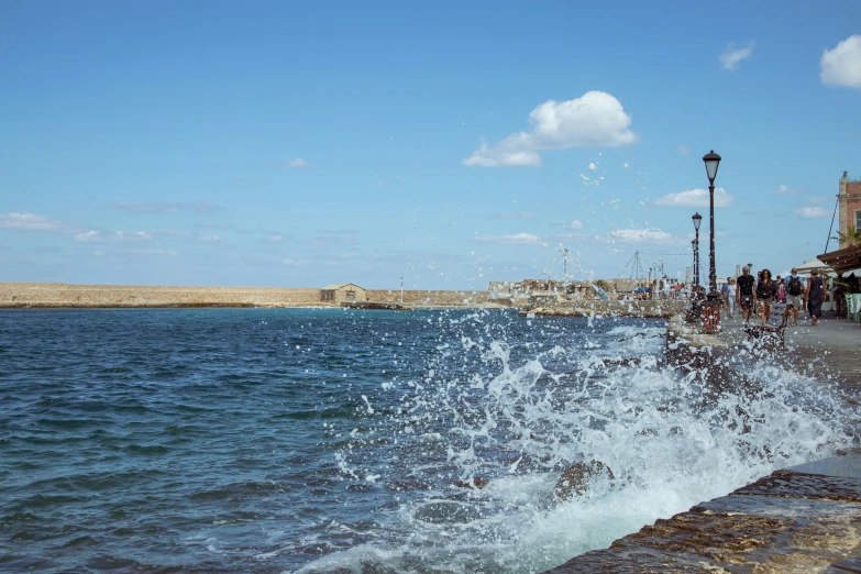 people walking on a sidewalk next to a body of water