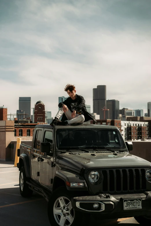 a man sitting on top of a parked jeep in a parking lot