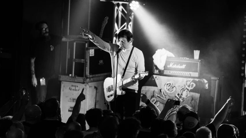 a man playing guitar and singing into a crowd