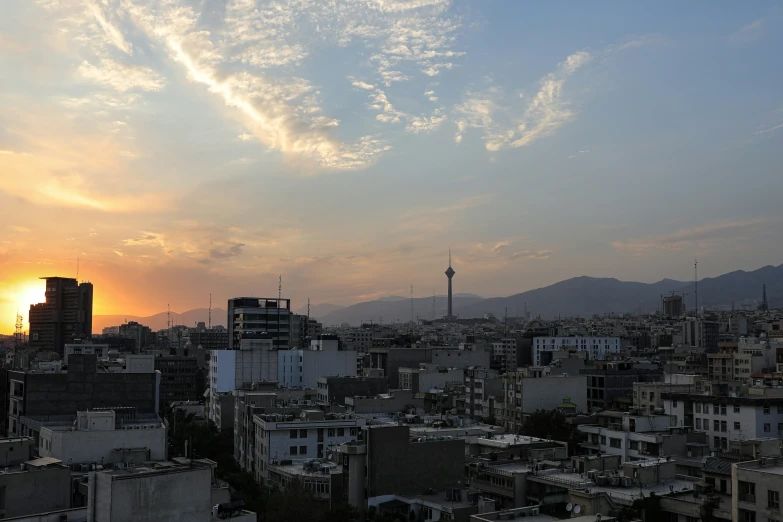 a sunset over buildings, with the sun behind them