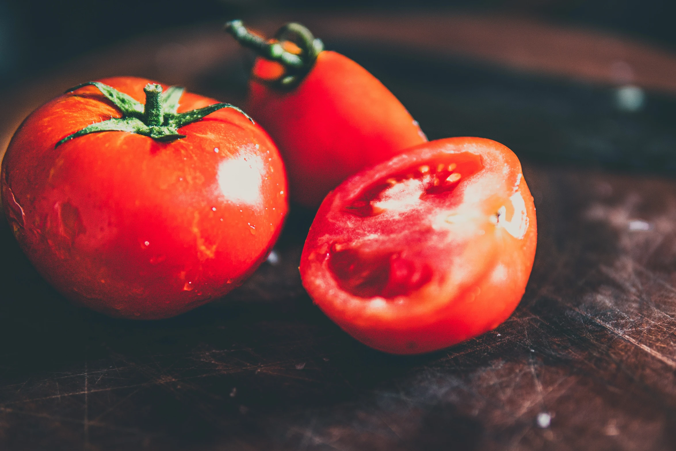 two tomatoes sitting on top of a  board