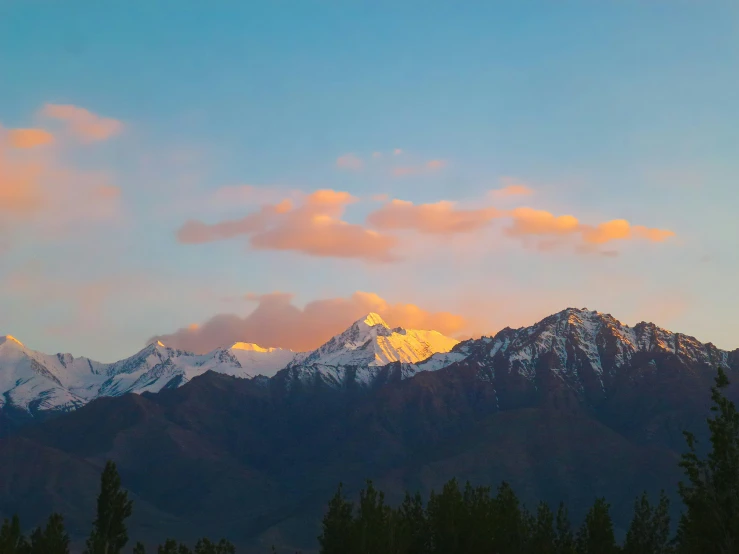 a mountainstop is silhouetted by a wintery sky