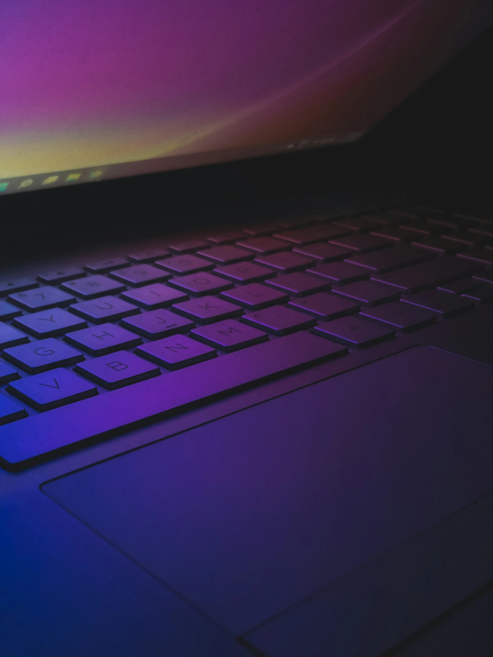 an apple laptop sits lit up purple with blue highlights