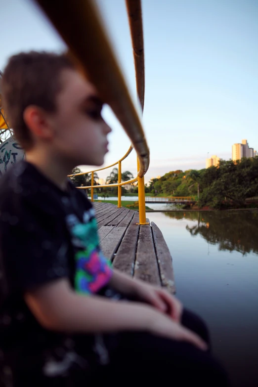 a young person sitting down on a wooden pier by the water