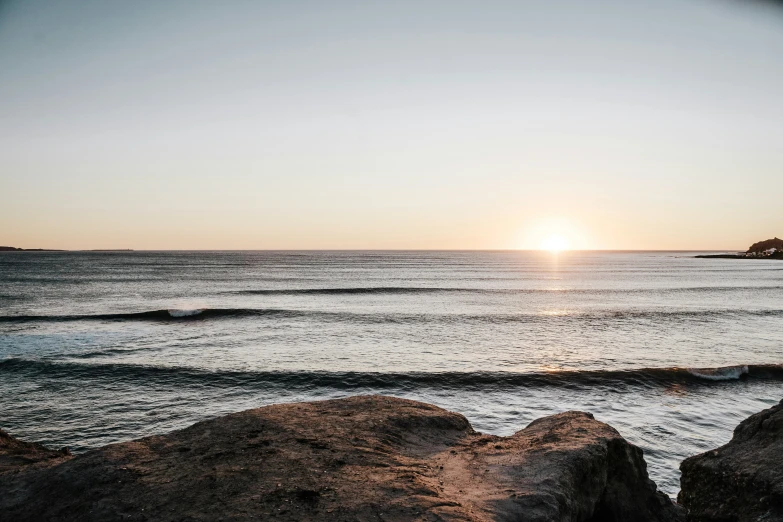 the sunset at a beach with a body of water