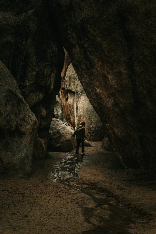 a man standing in a cave between some rocks