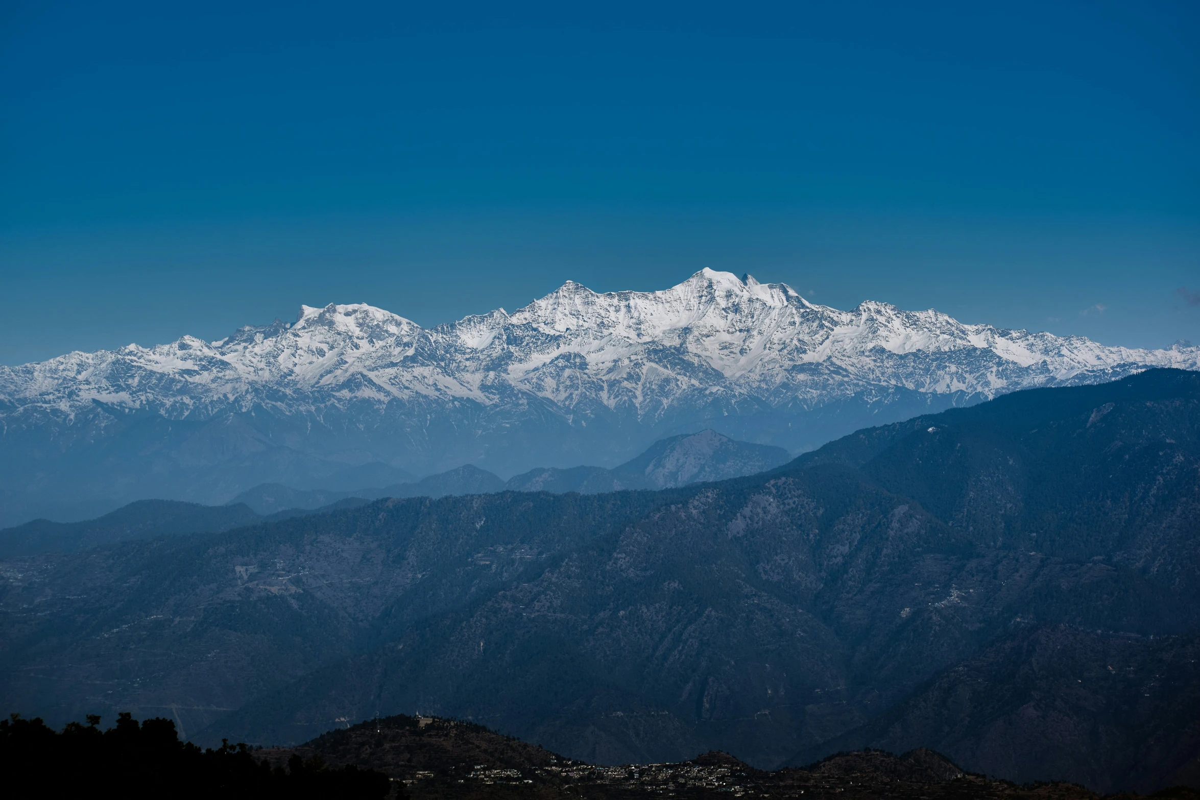 a mountain range is dotted with snow capped peaks